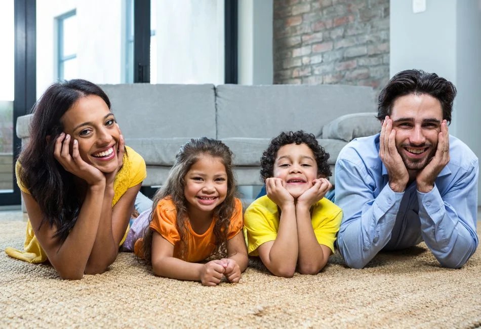 smiling family on carpet in the living room